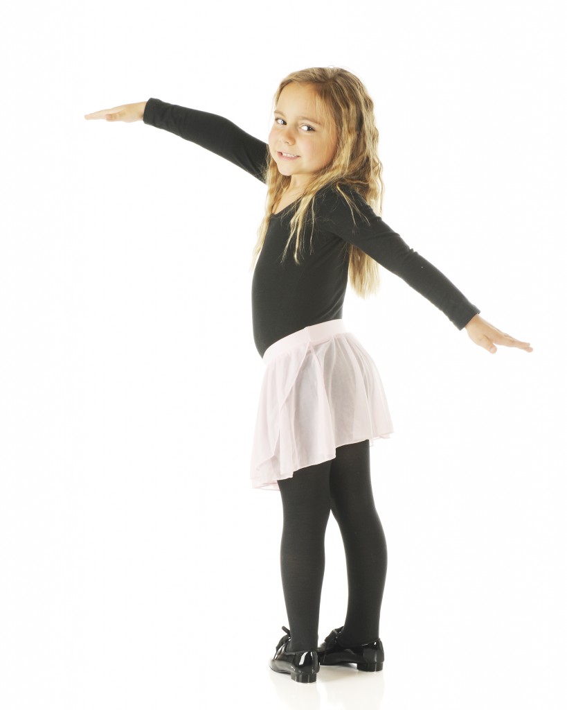An adorable kindergarten dancer with her arms spread in her leotards, tutu and tap shoes. On a white background.